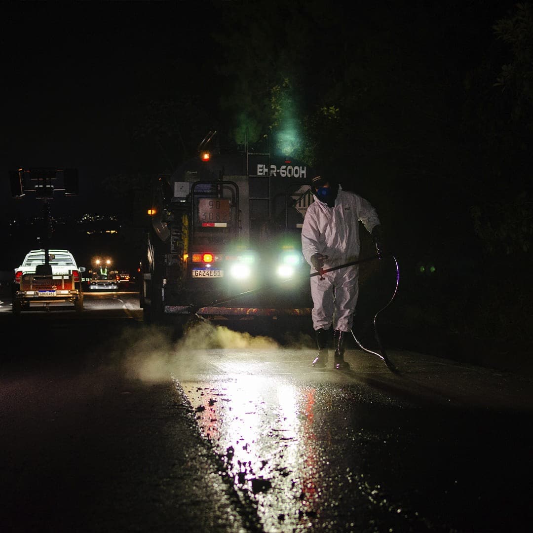Pavimentação asfáltica noturna com pavimentadora e iluminação